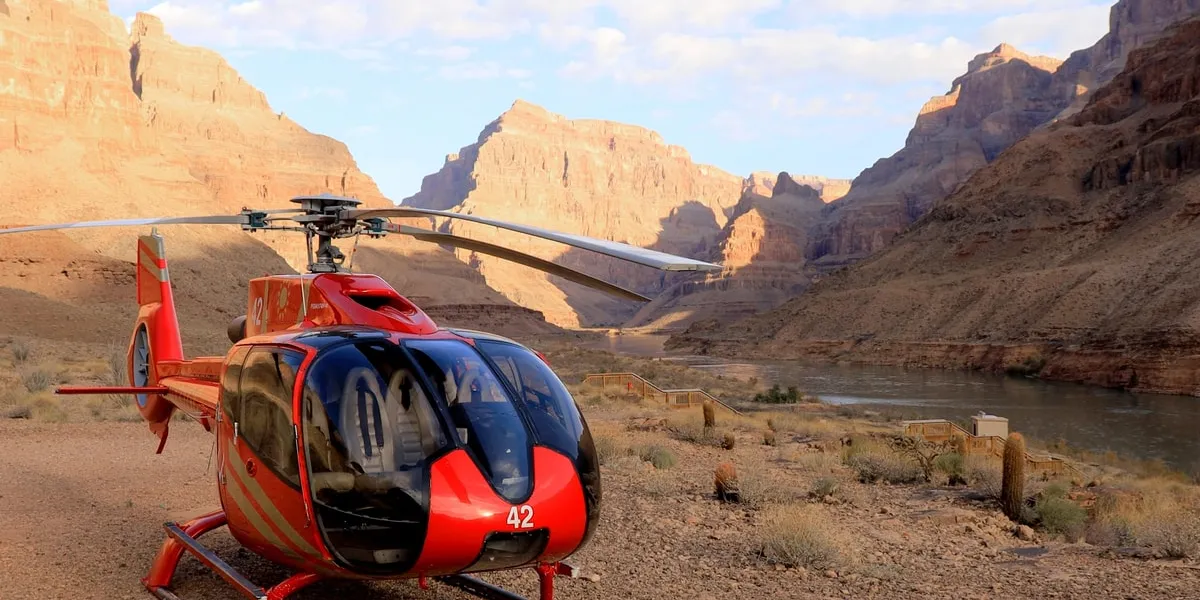 Red Papillon helicopter on the canyon-floor landing site beside the Colorado River at Grand Canyon West