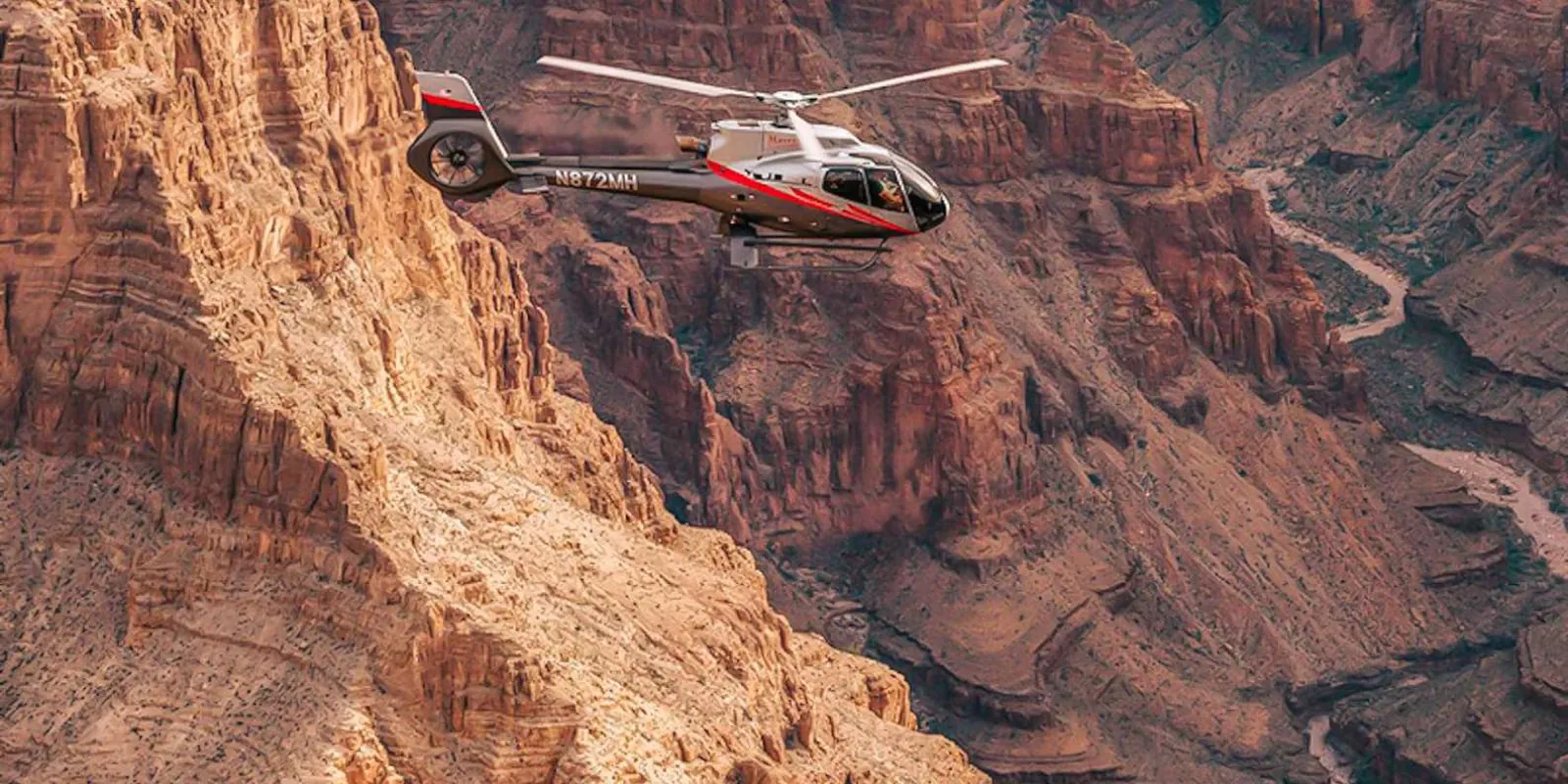 Helicopter tracking the layered cliff face of the Grand Canyon West rim