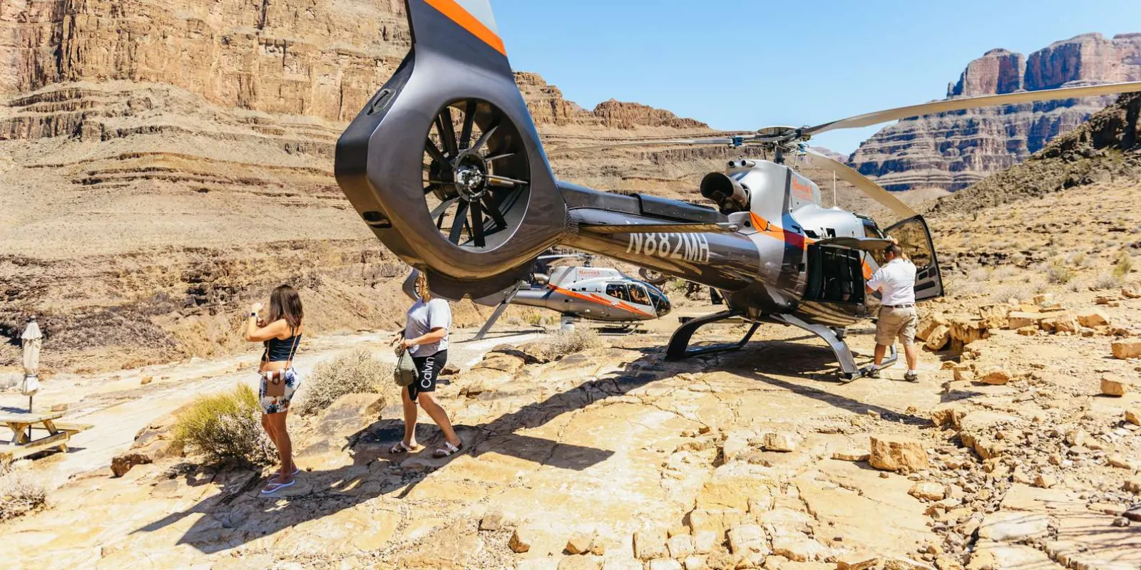 Guests stepping out of a Maverick helicopter at the canyon-floor landing site