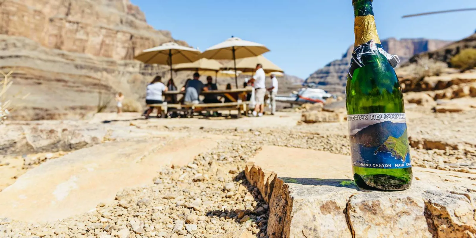 Shaded picnic tables and a champagne bottle at the private canyon-floor landing site