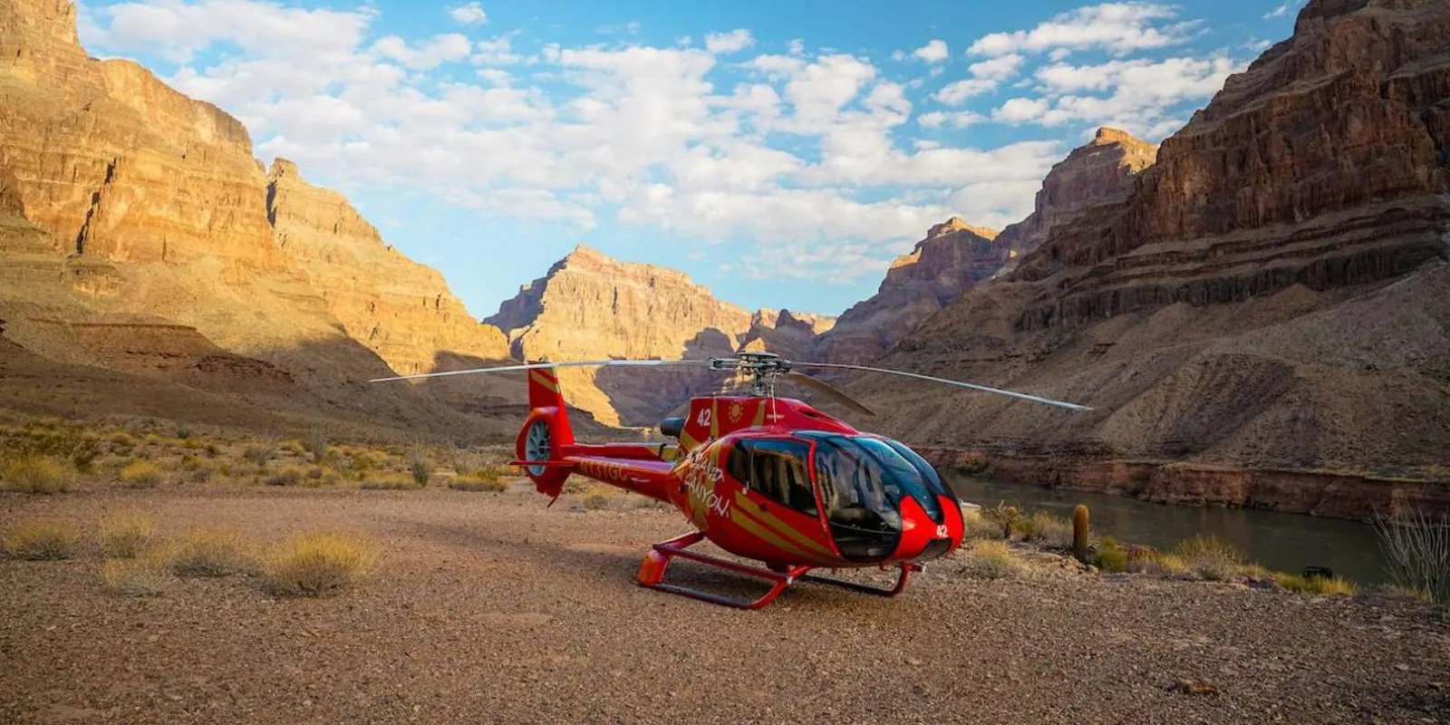 Red EcoStar helicopter on its landing pad deep inside Grand Canyon West, canyon walls rising behind