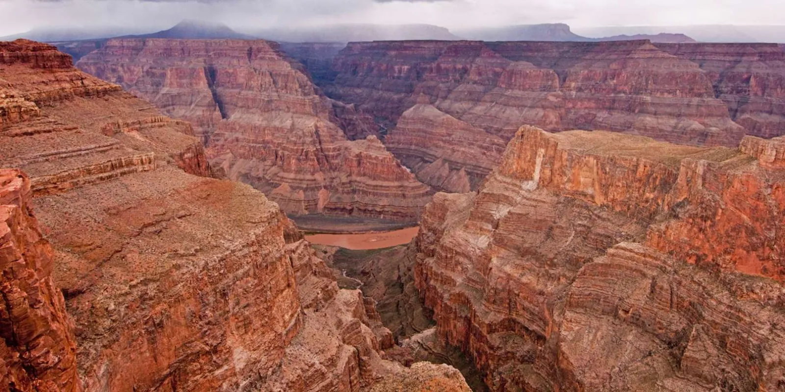 Aerial view of layered red canyon walls dropping to the Colorado River
